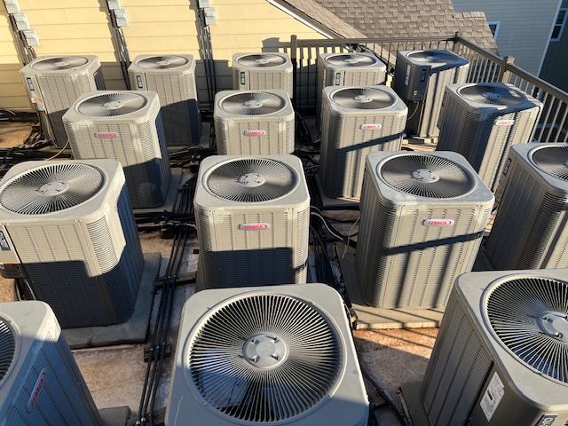 A bunch of air conditioners are sitting on top of a roof.