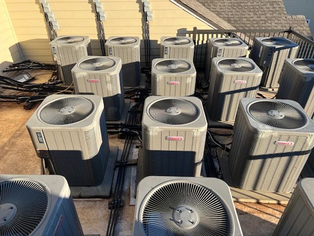 A bunch of air conditioners on a roof are having maintenance checks, A yearly service offered by John's Heating, cooling, and appliance repair
 on top of a roof.