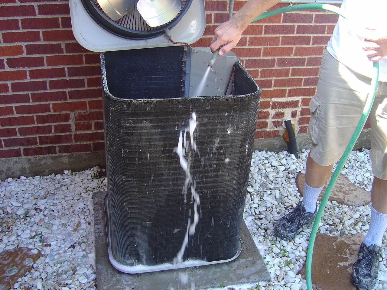 Cleaning an AC Unit with coil cleaner and rinsing it with water from a hose. Maintenance Visit from John's Heating, Cooling, and Appliance Repair