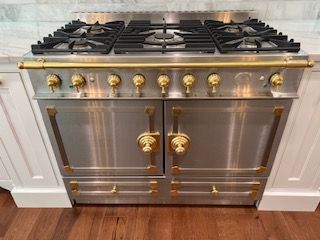 A stainless steel stove with gold handles and knobs