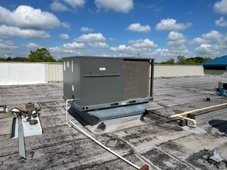 A large air conditioner being serviced by John's Heating, Cooling, and Appliance Repair is sitting on top of a roof in Peachtree City.

