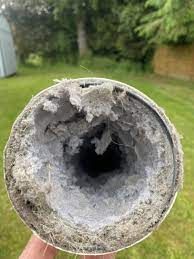 A person is holding a very dirty pipe in their hand.