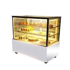 A display case filled with cakes and pastries on a white background.