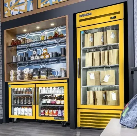 A yellow refrigerator filled with bags and bottles