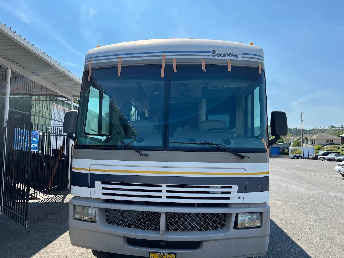 Tan and blue RV parked outside under a bright sky.