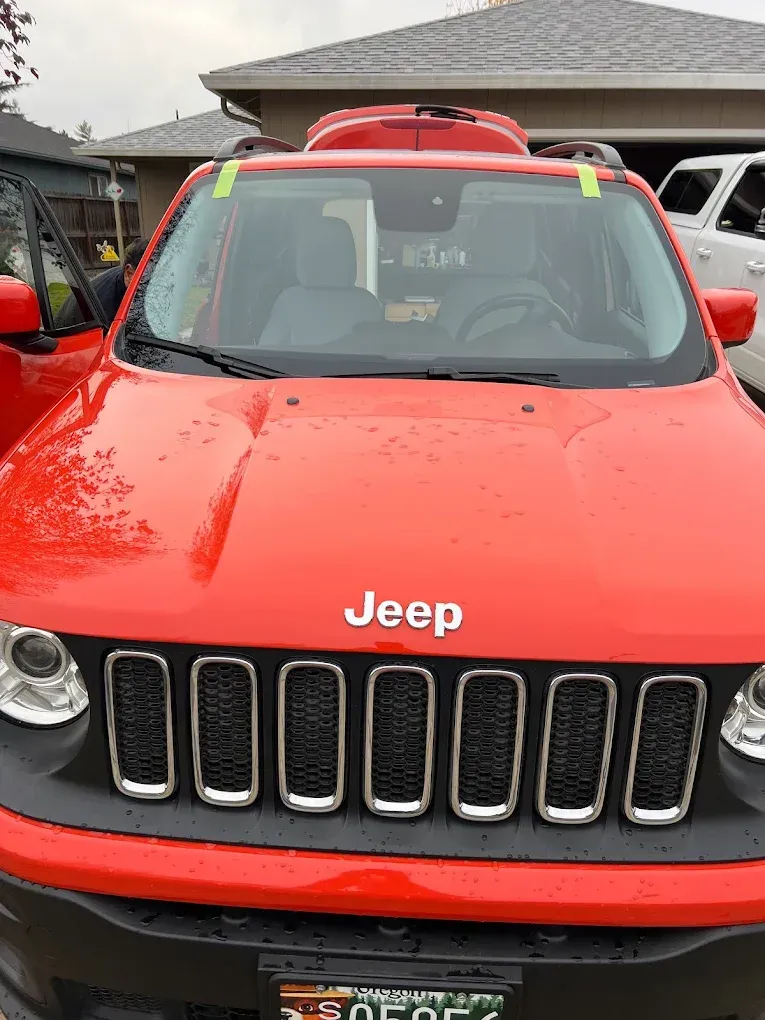 Red Jeep Renegade with a black front grill parked outside.