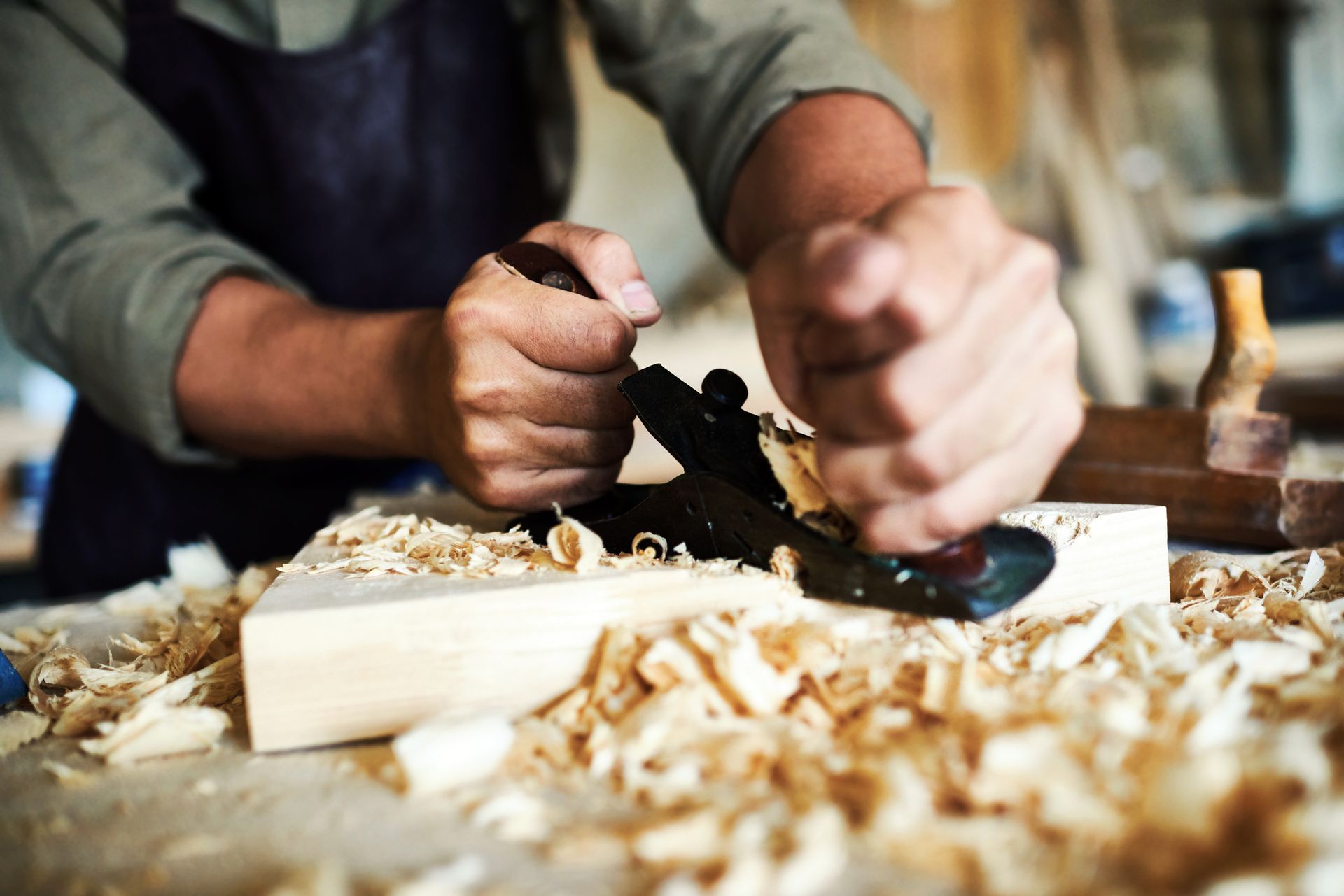 A man is using a plane to carve a piece of wood.