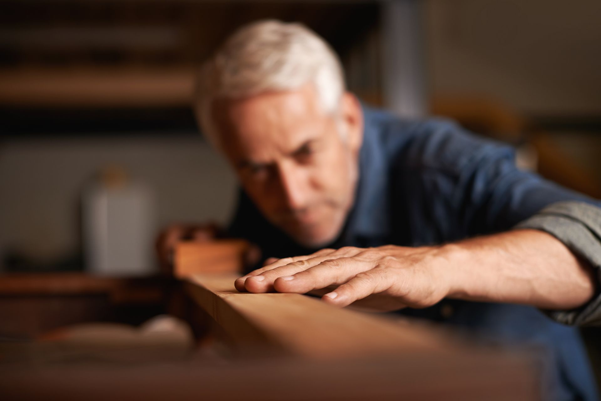 A man is working on a piece of wood in a workshop.