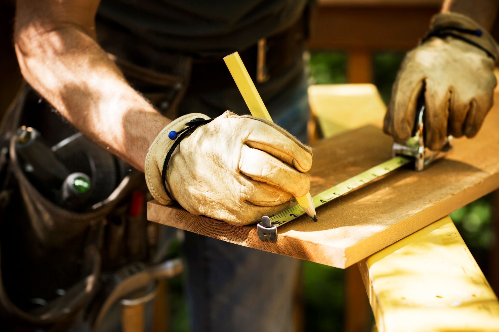A man is measuring a piece of wood with a tape measure.
