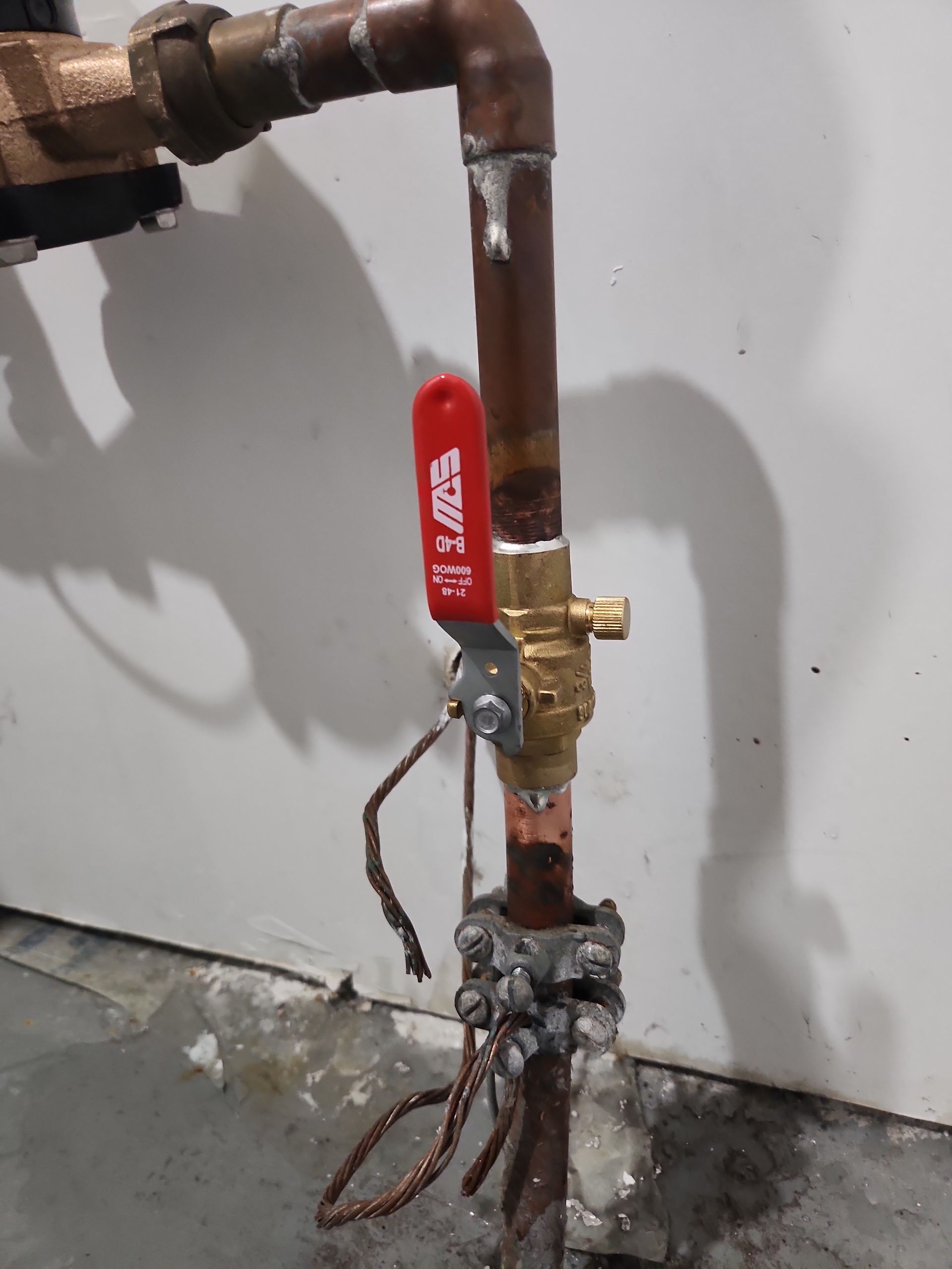 Copper pipe with a red handled valve. Grounding clamp and wires attached.