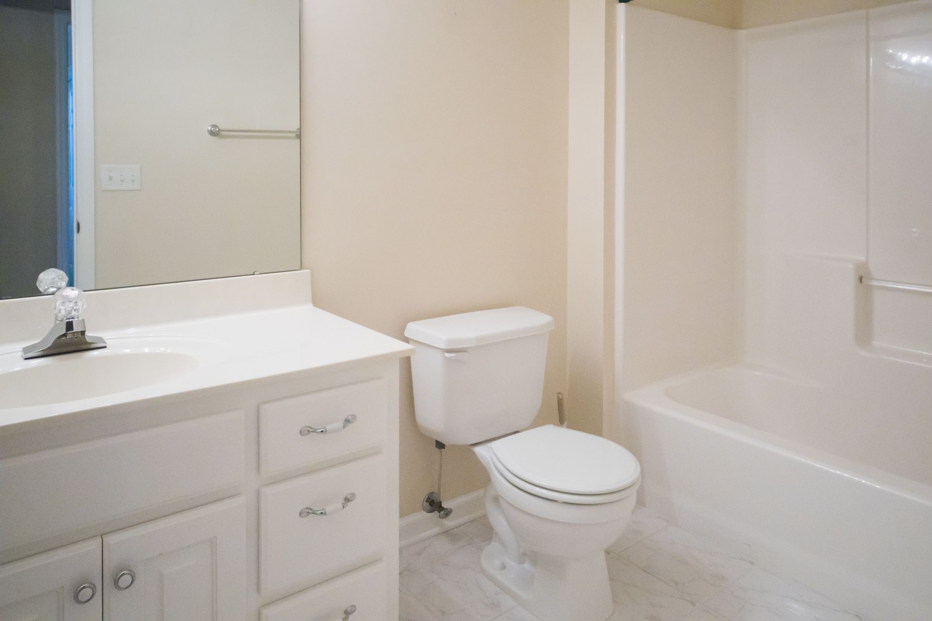 White bathroom with sink, toilet, and bathtub. Beige walls, light gray floor.