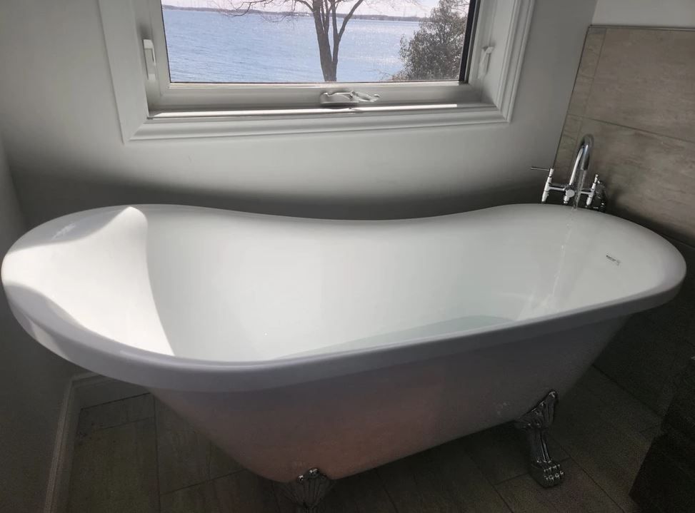 White clawfoot bathtub near a window, natural light, and scenic view.