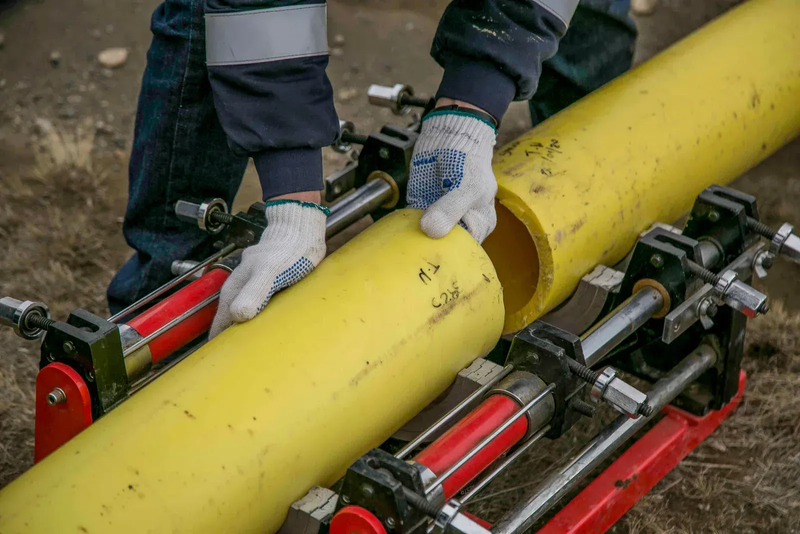 Hands tightening a brass pipe fitting, part of a plumbing system.