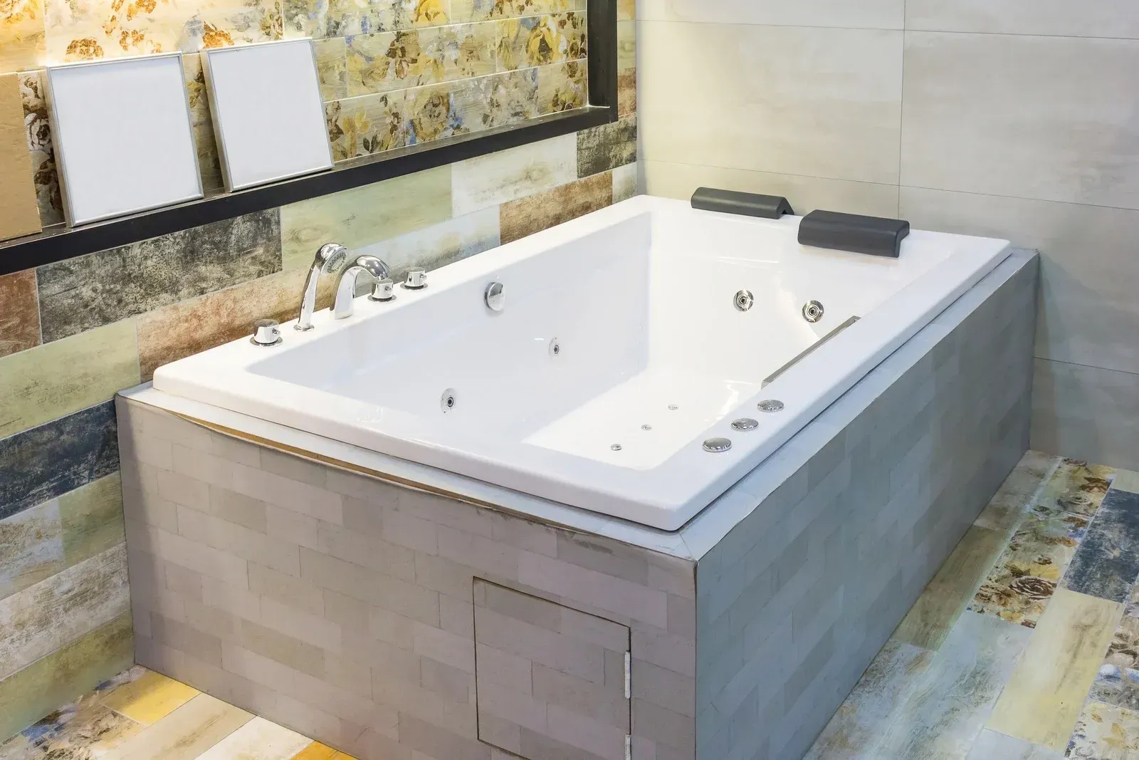 White jacuzzi tub built into tiled wall, with a mirror above and jets.