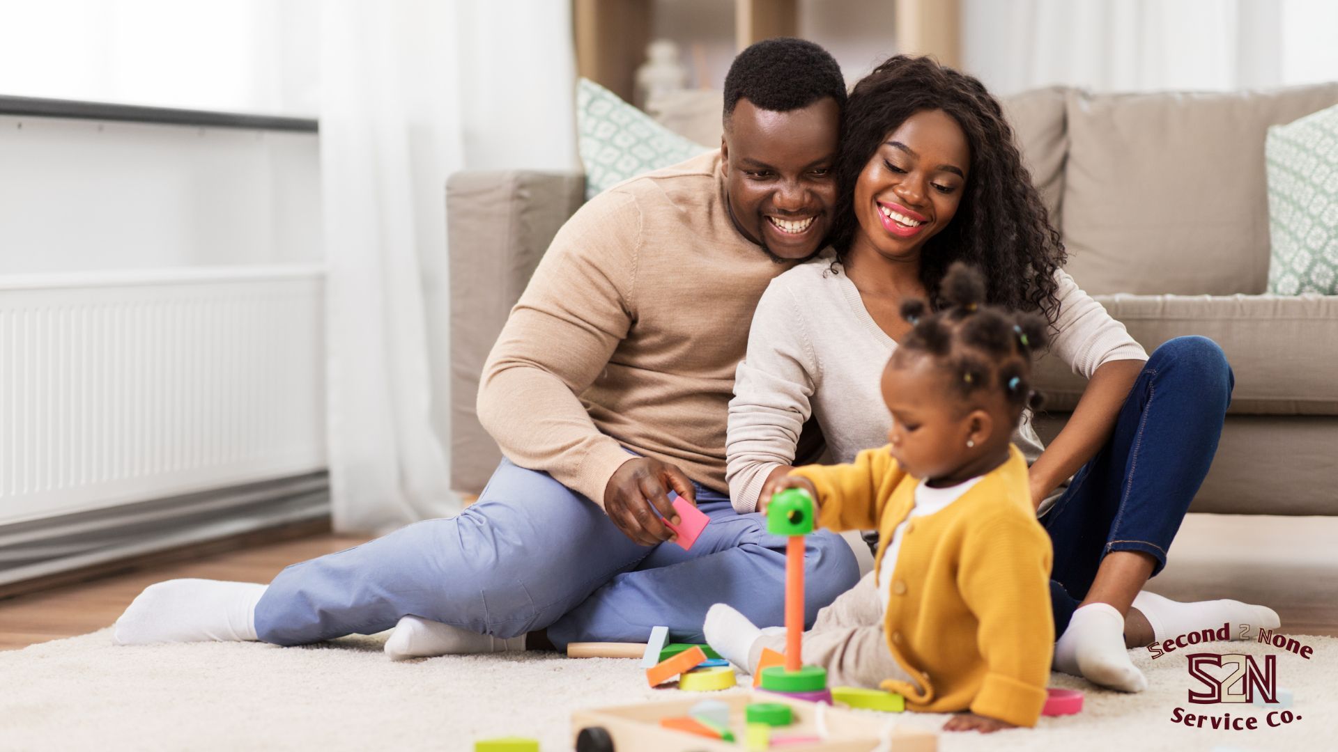 A man , woman and child are sitting on the floor playing with toys in Columbus ga