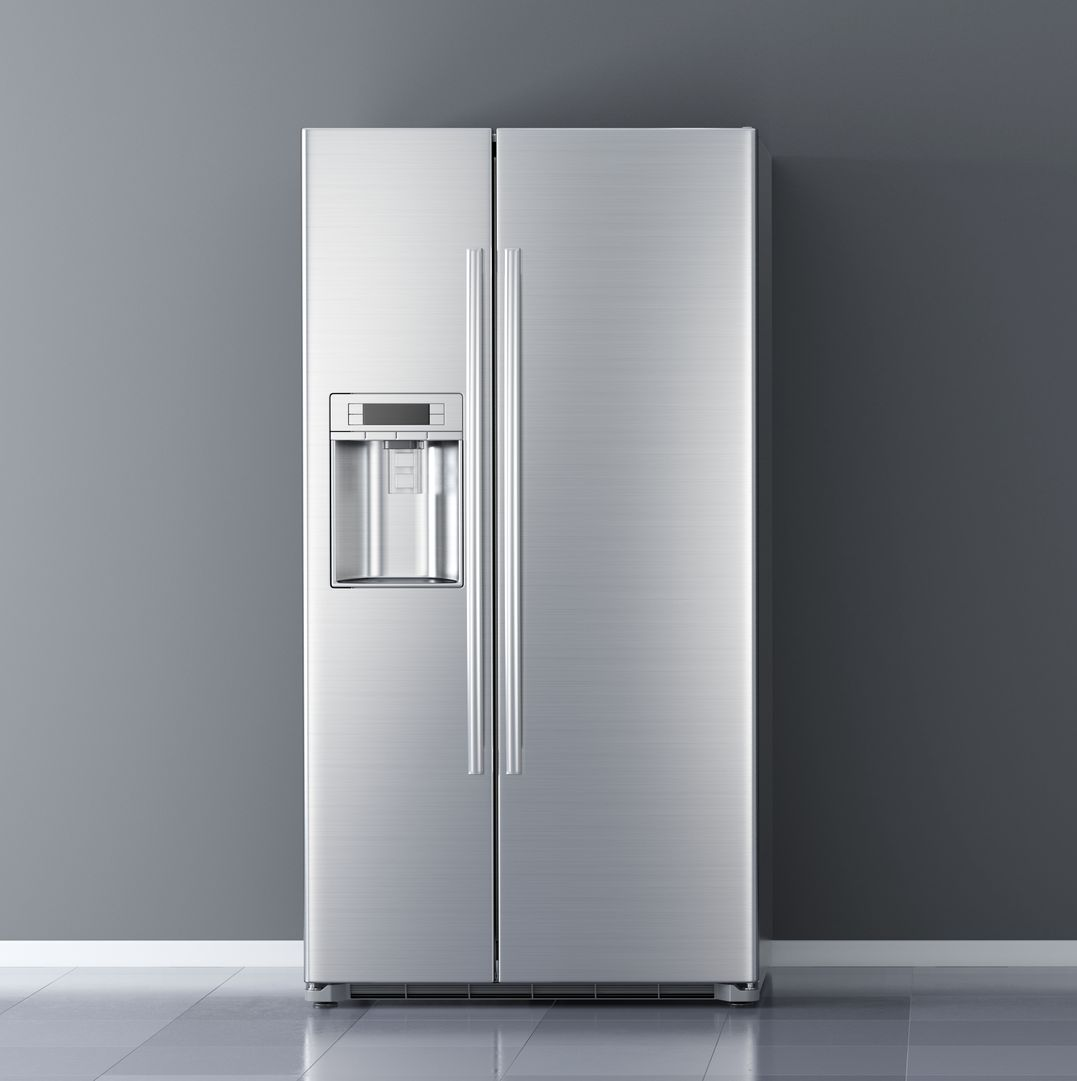 A stainless steel side-by-side refrigerator with a water and ice dispenser, standing against a dark grey wall.