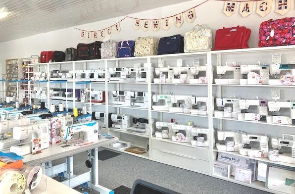 A showroom with shelves with lots of sewing machines on. To the left of the picture are Jack industrial machines.