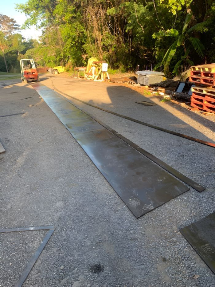 A Forklift Is Driving Down A Road Next To A Pile Of Pallets — Belt Maintenance & Supplies Pty Ltd In Nindaroo, QLD