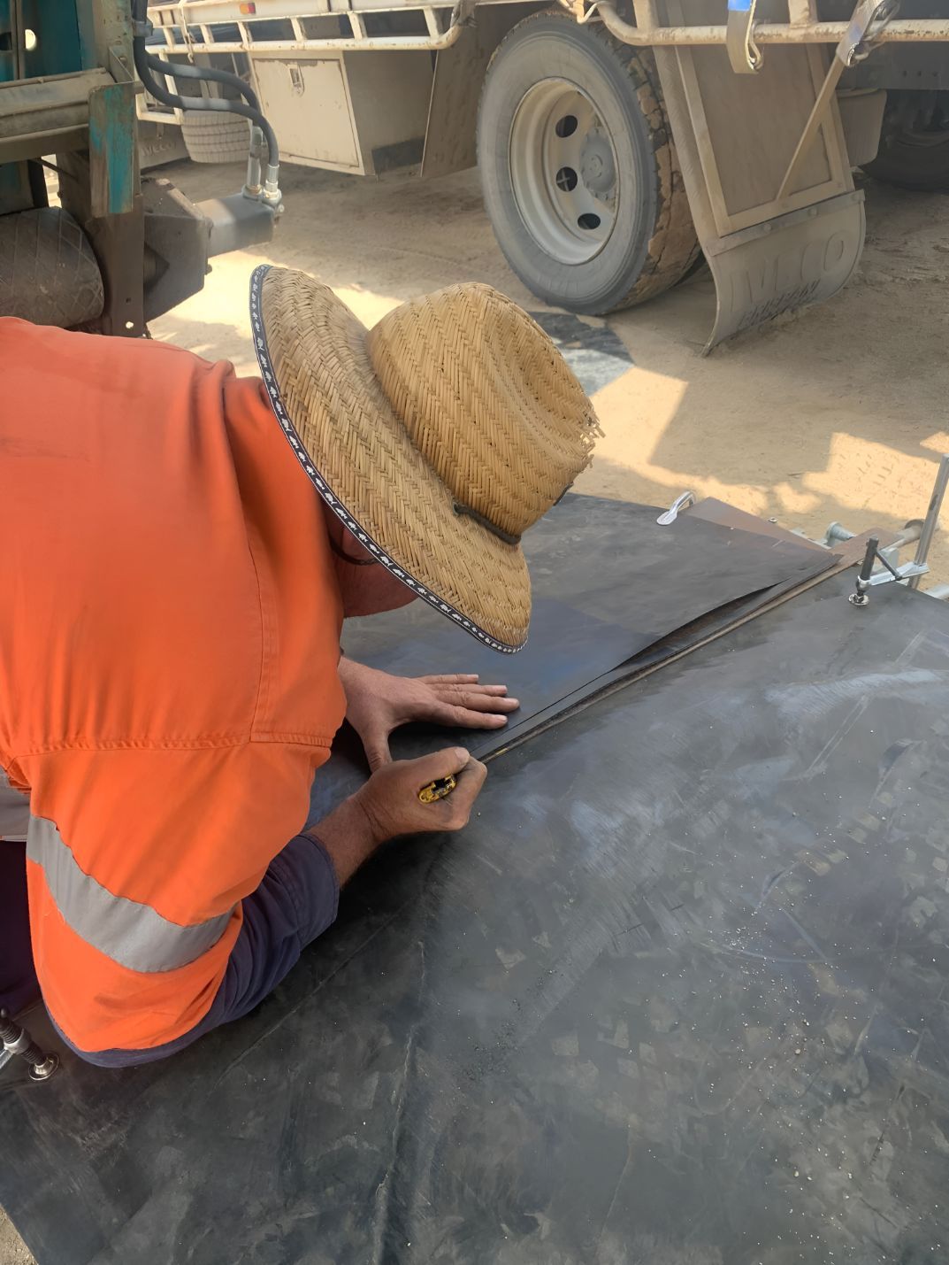 A Man Wearing A Straw Hat Is Kneeling Down On The Ground — Belt Maintenance & Supplies Pty Ltd In Nindaroo, QLD
