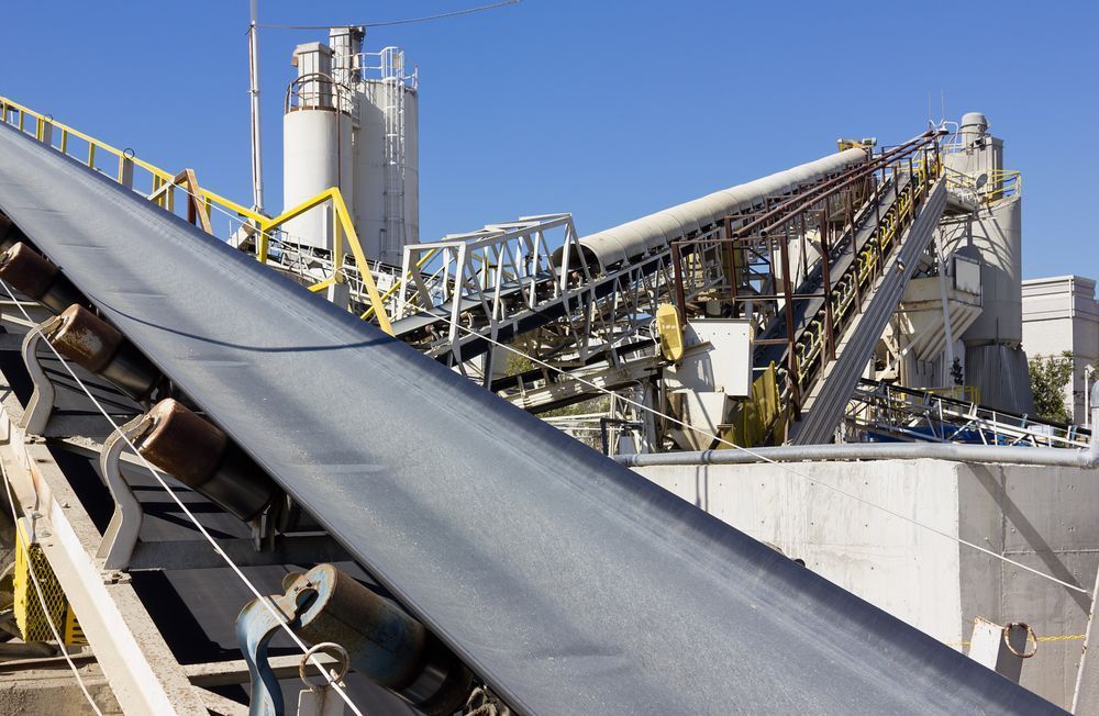 A Conveyor Belt In A Factory With A Blue Sky In The Background — Belt Maintenance & Supplies Pty Ltd In Nindaroo, QLD
