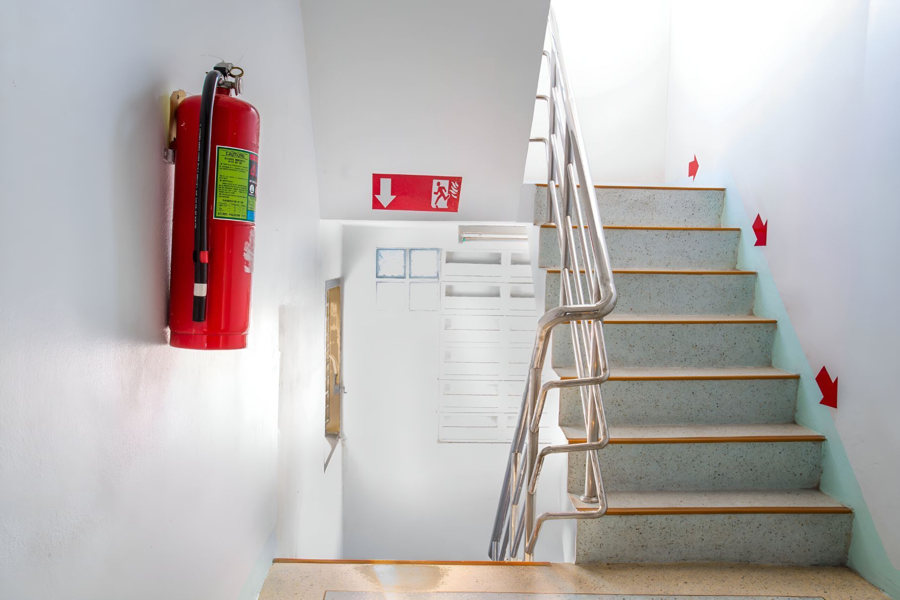A Fire Extinguisher Is Hanging On The Wall Next To A Set Of Stairs — Belt Maintenance & Supplies Pty Ltd In Nindaroo, QLD