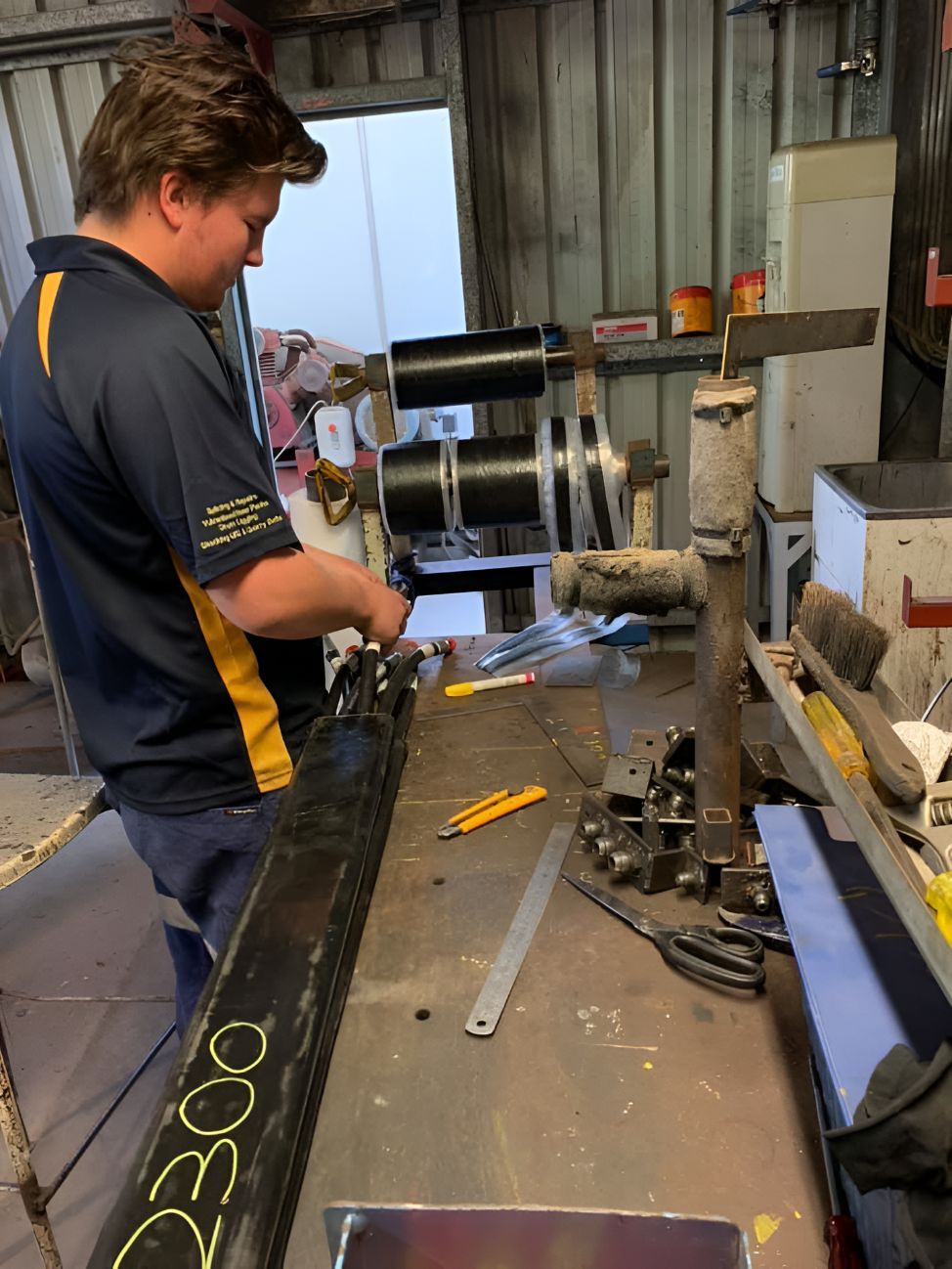 A Man Is Working On A Piece Of Metal That Says 2300 On It — Belt Maintenance & Supplies Pty Ltd In Nindaroo, QLD