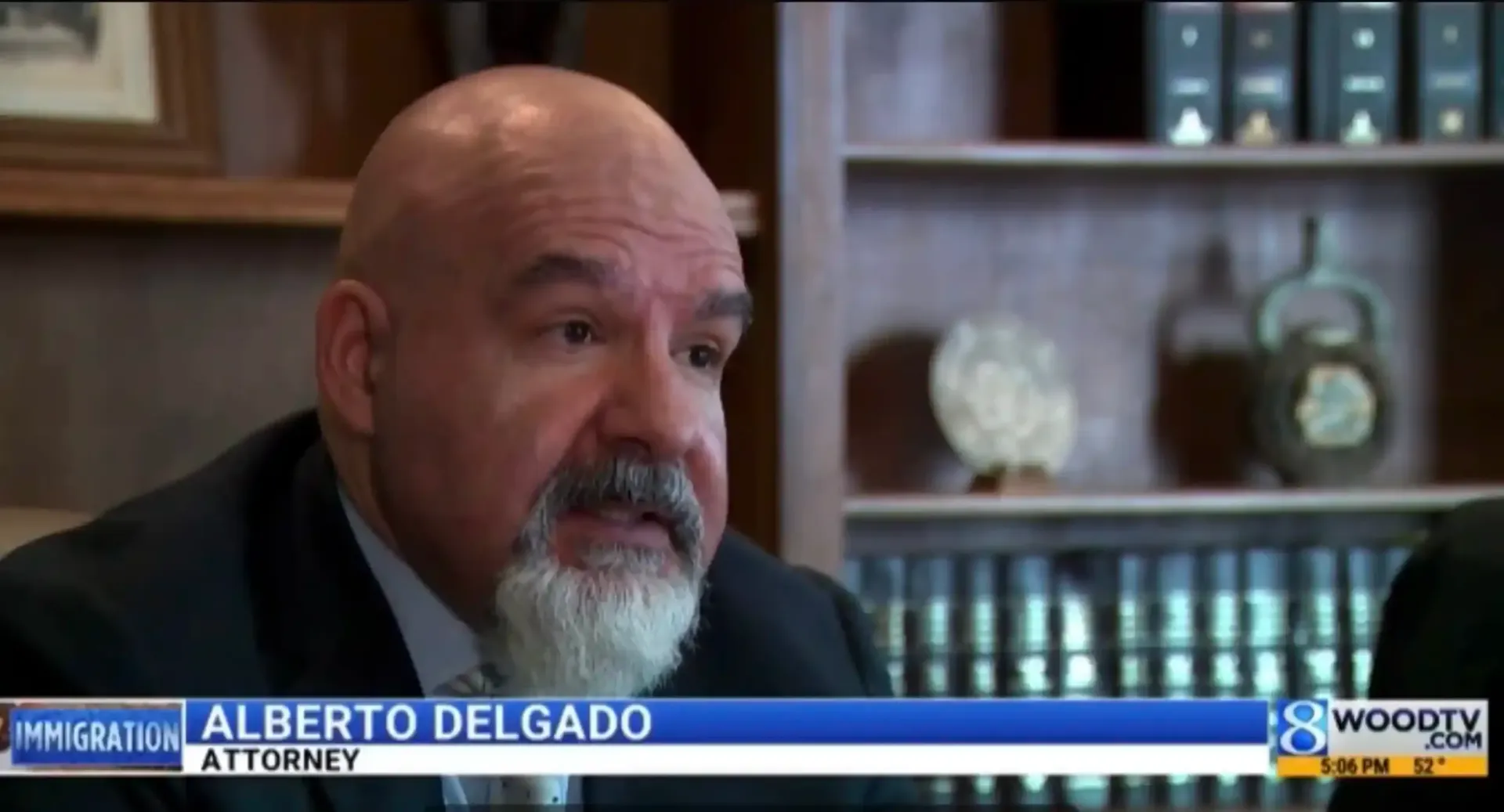 Alberto Delgado, attorney, speaks at a desk with a bookshelf in the background.