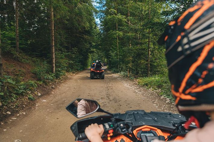 A person is riding an atv down a dirt road.