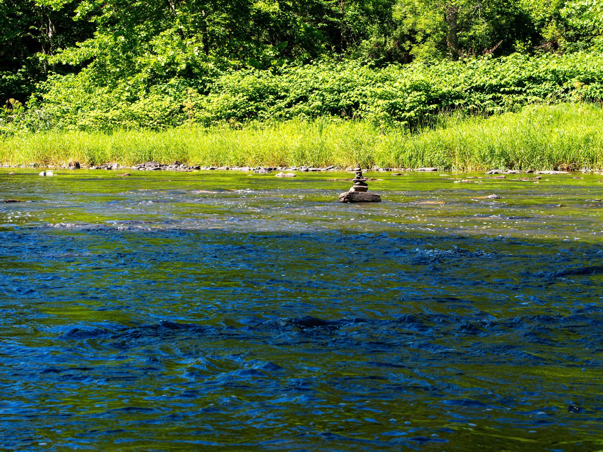 A person is sitting on a rock in the middle of a river