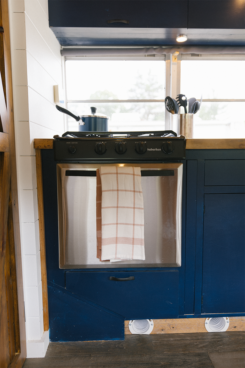 A kitchen with blue cabinets and a stove with a towel hanging out of it.
