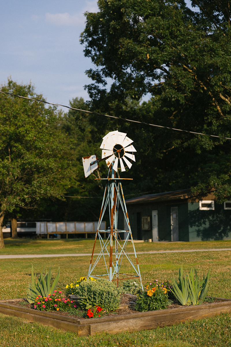 A windmill is sitting in the middle of a lush green field.