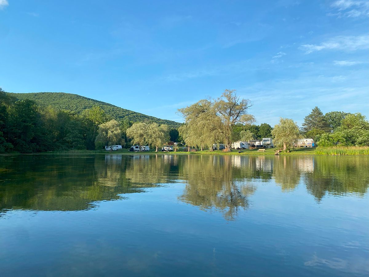 A lake surrounded by trees and mountains on a sunny day