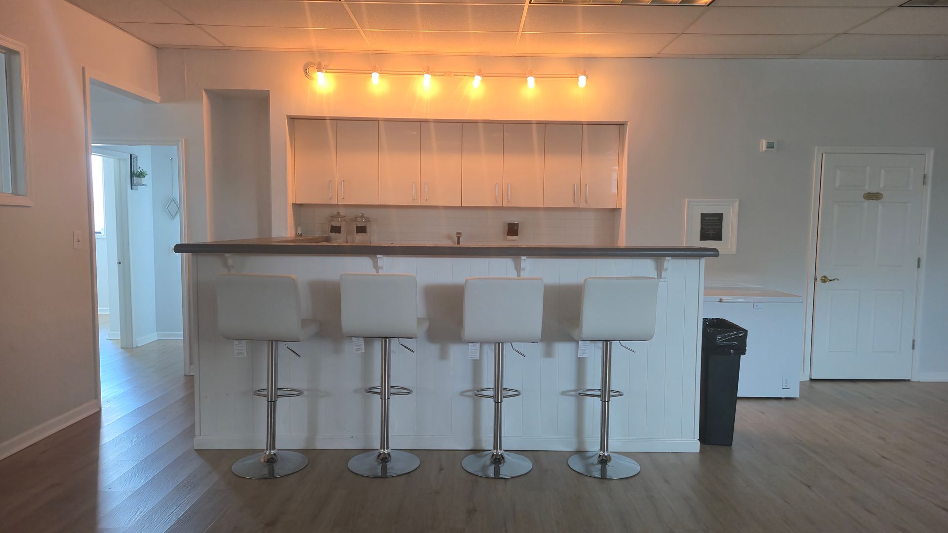 A kitchen with a bar and stools and glasses on the counter.