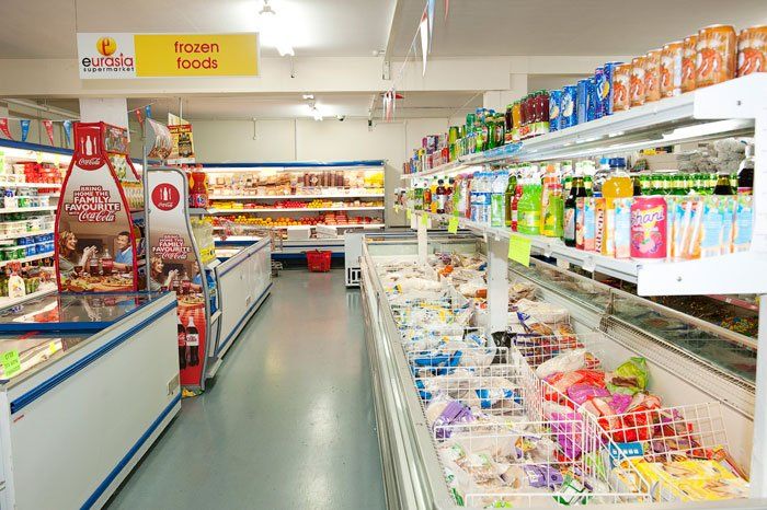 A supermarket aisle filled with lots of frozen foods.