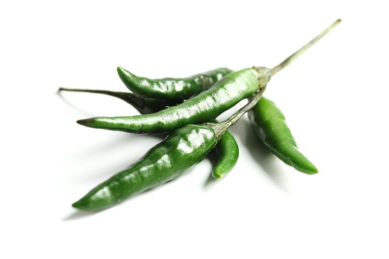 A bunch of green peppers on a white background