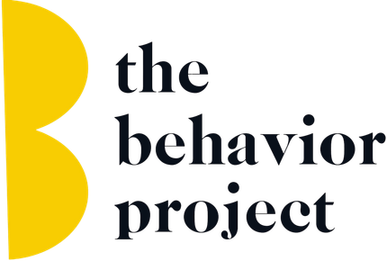 The Behavior Project logo with yellow abstract shape and black text on white background