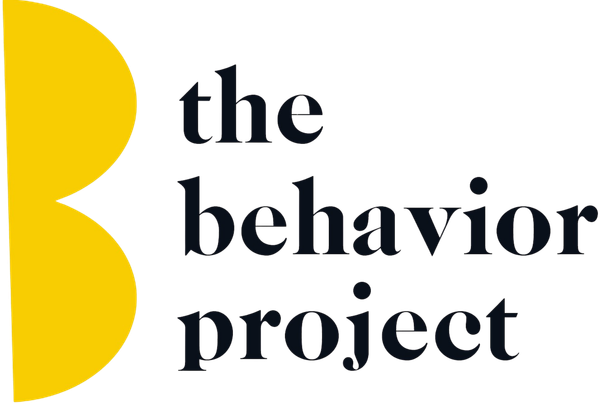 The Behavior Project logo with yellow abstract shape and black text on white background