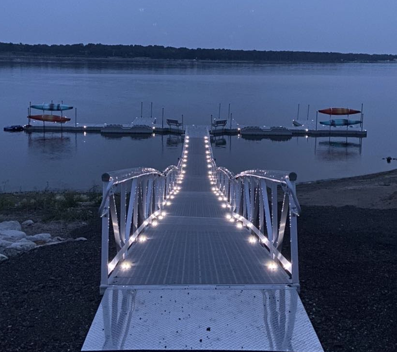 a dock with lights on it leading to a body of water