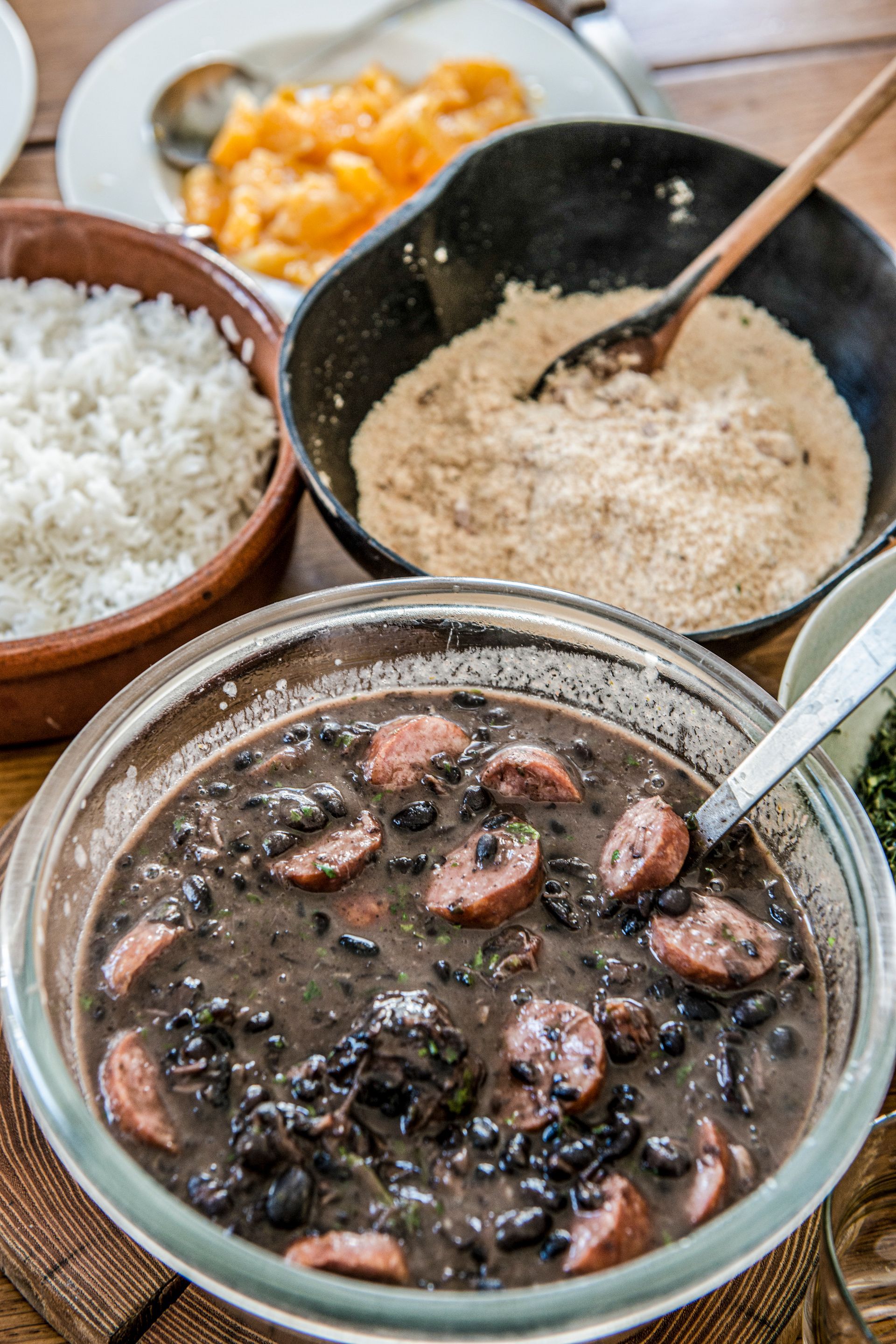 Feijoada, stufato brasiliano di fagioli neri con salsiccia, servito con riso, farofa e arance.