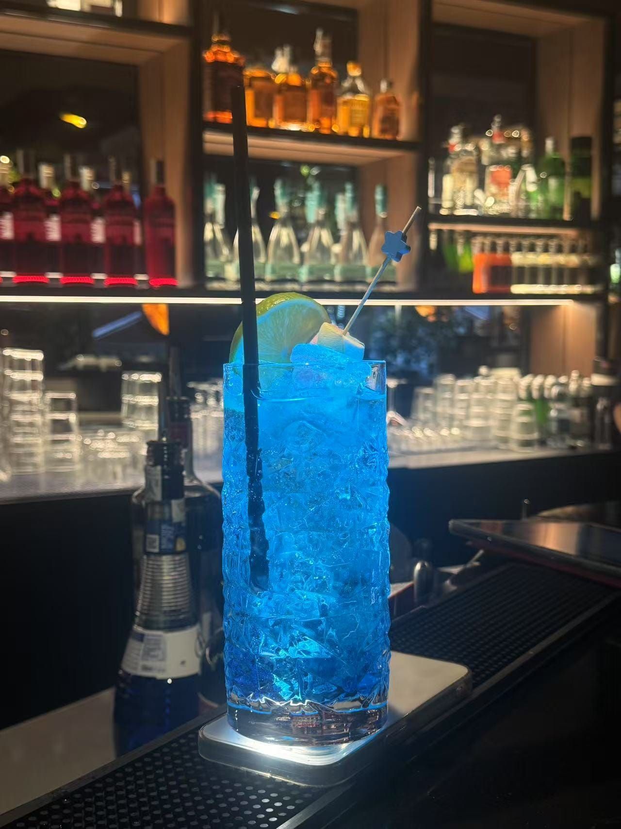 Parete color verde acqua con opere d'arte incorniciate e scritta al neon