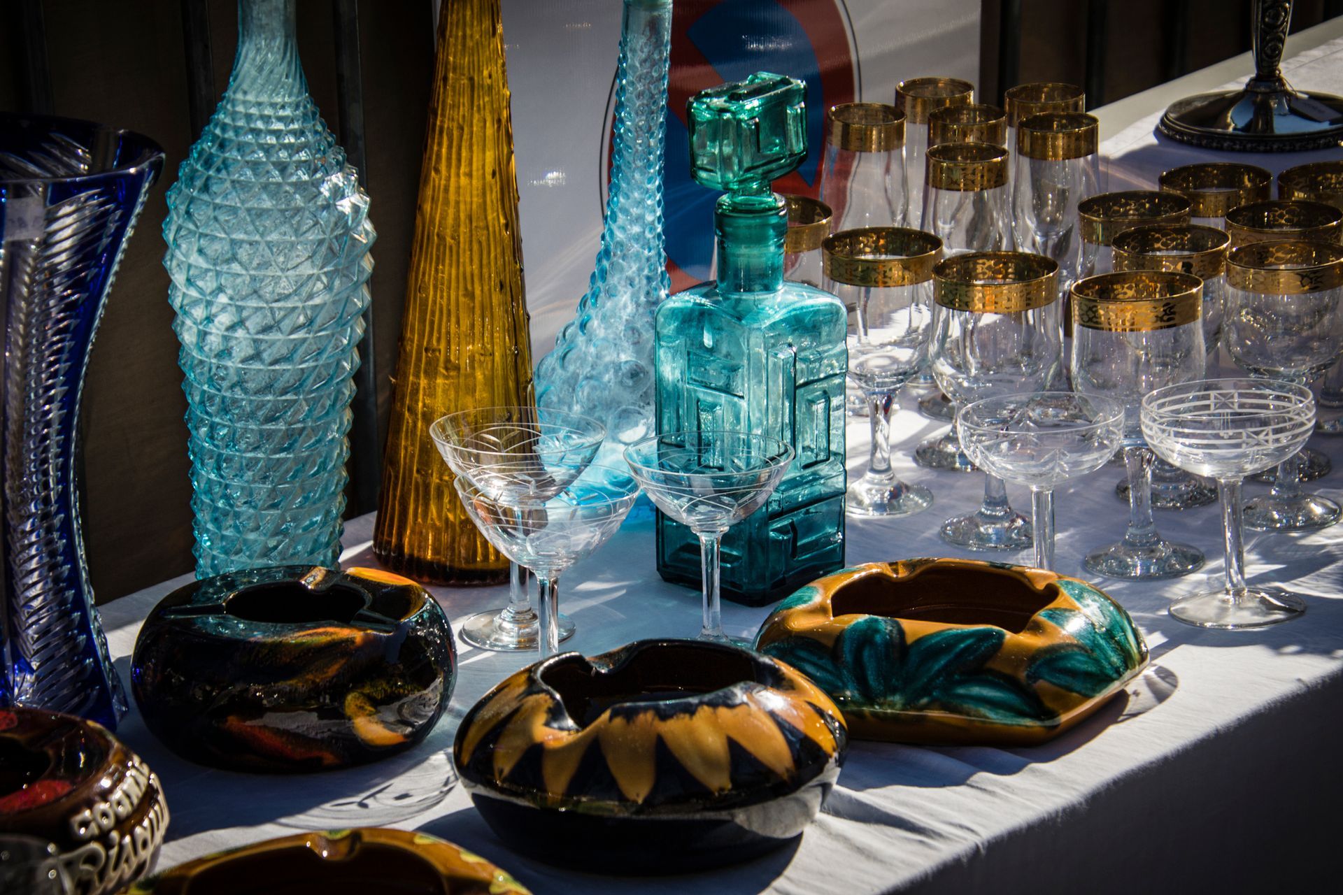 Un tavolo sormontato da vasi, bicchieri da vino e posacenere.