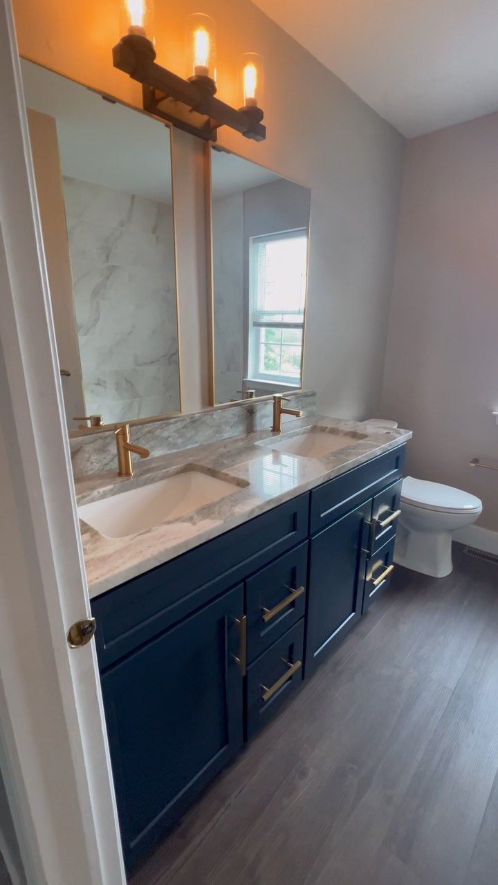 A bathroom with two sinks , a toilet and a mirror.