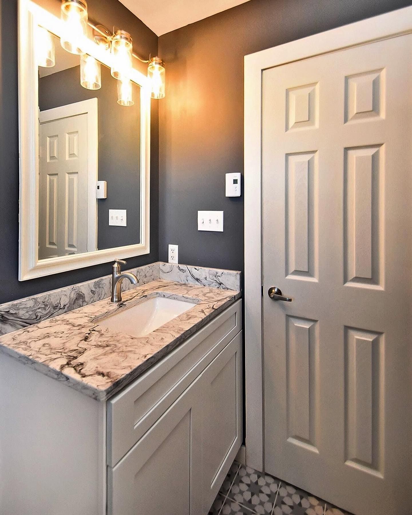 A bathroom with a sink , mirror and door