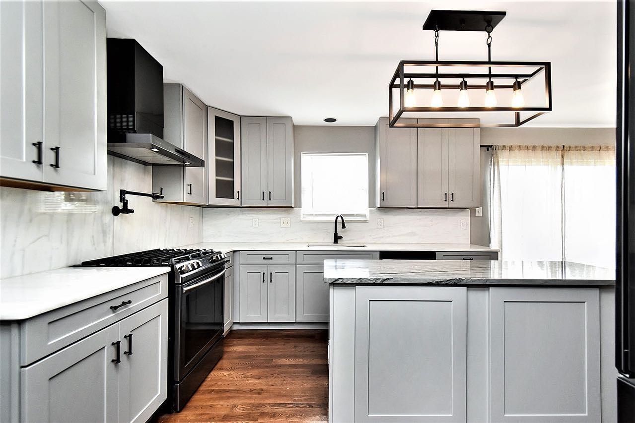 A kitchen with white cabinets , black appliances , and a large island.