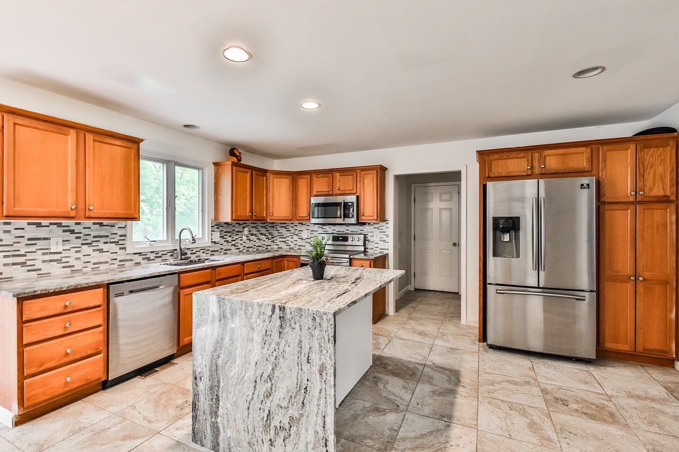 A kitchen with stainless steel appliances , granite counter tops , and wooden cabinets.