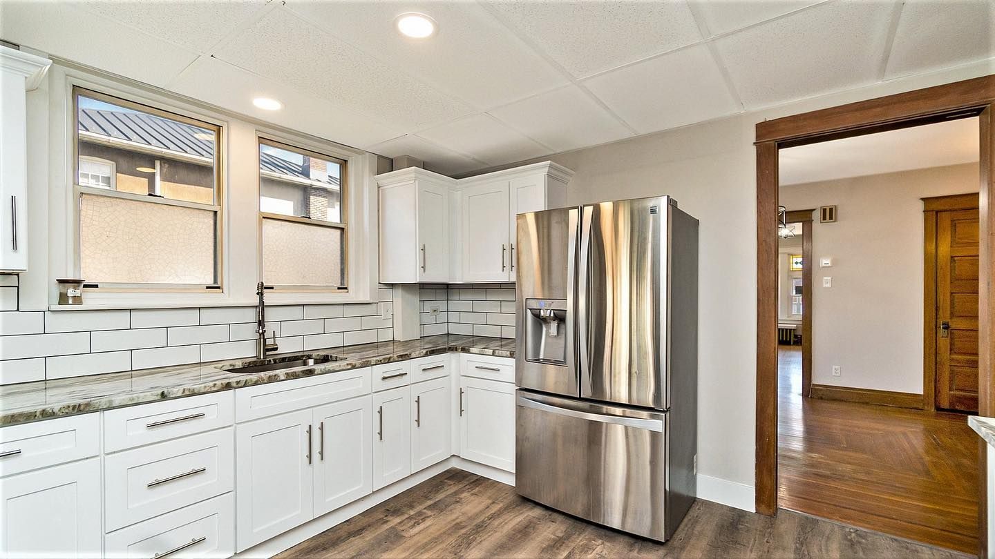 A kitchen with white cabinets and a stainless steel refrigerator.