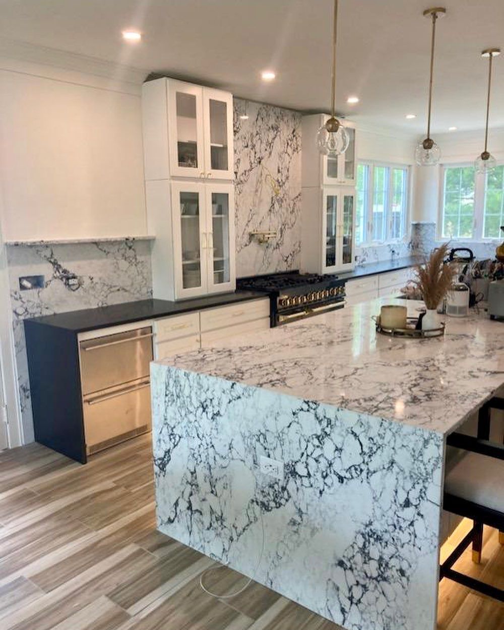 A kitchen with a large island and marble counter tops.