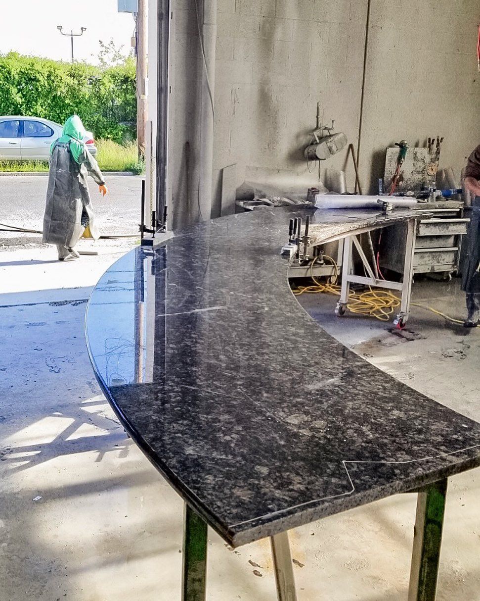 A black granite table in a garage with a man standing in the background