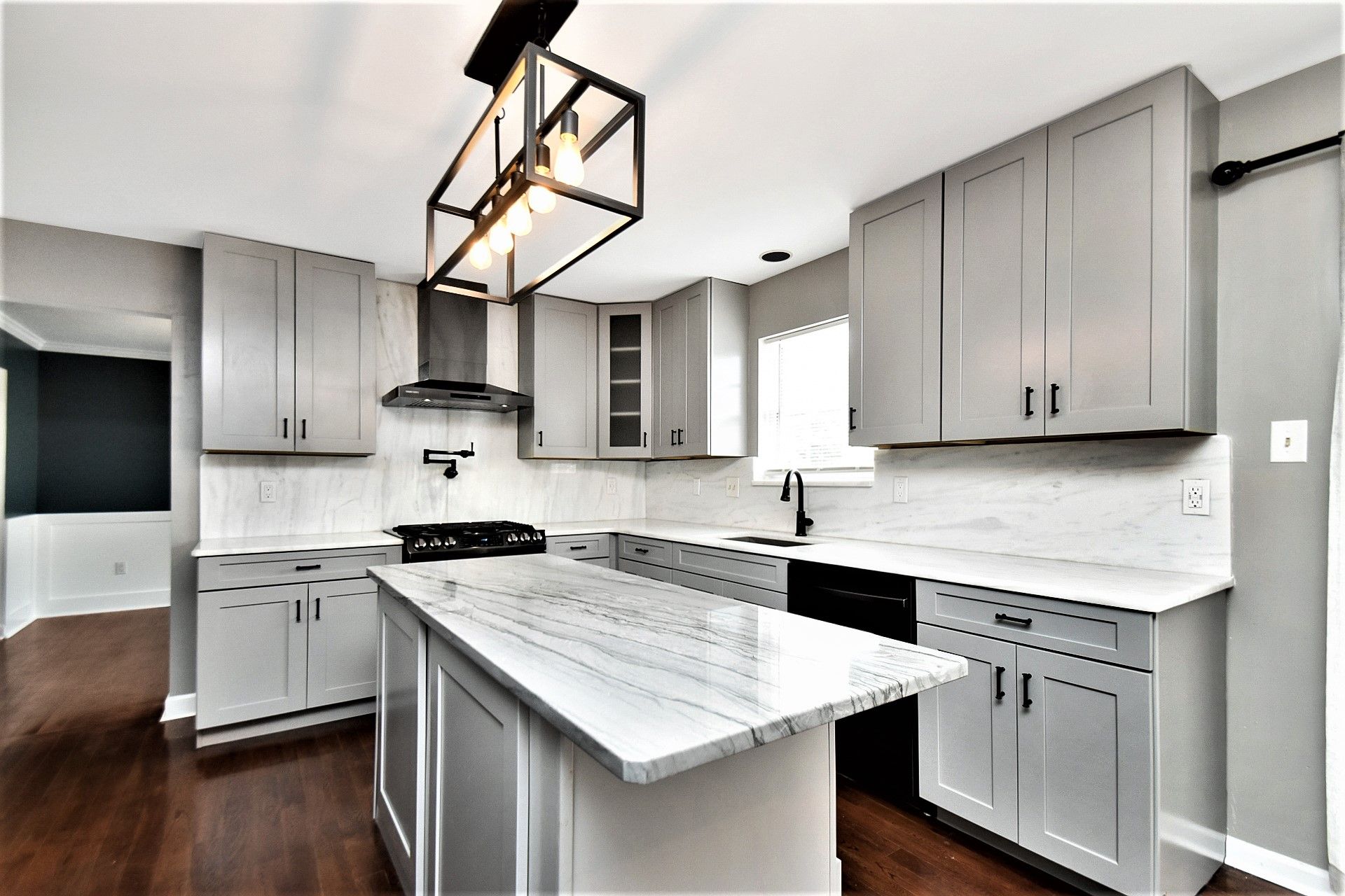 A kitchen with gray cabinets and white counter tops and a large island in the middle.