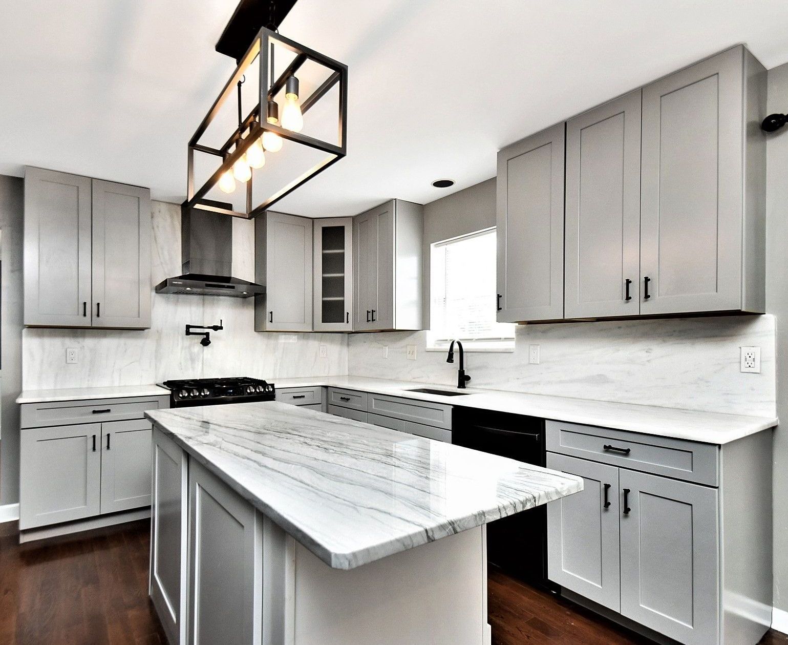 A kitchen with white cabinets and a large island in the middle.